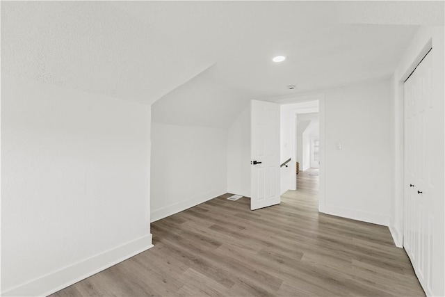 bonus room with vaulted ceiling, baseboards, and wood finished floors