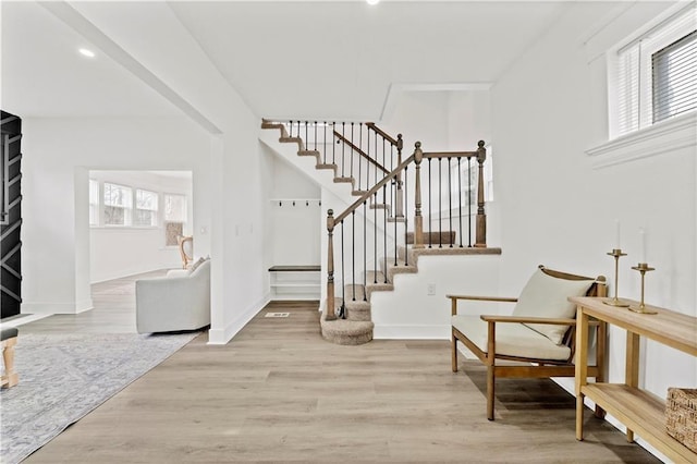 entrance foyer featuring wood finished floors, plenty of natural light, baseboards, and stairs