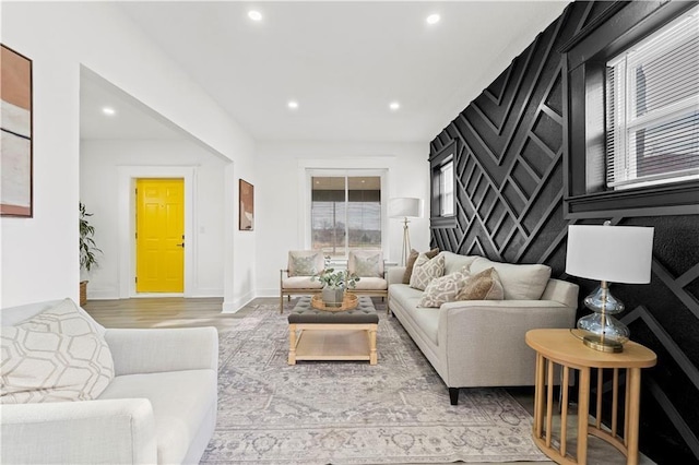 living area featuring baseboards, an accent wall, light wood-type flooring, and recessed lighting