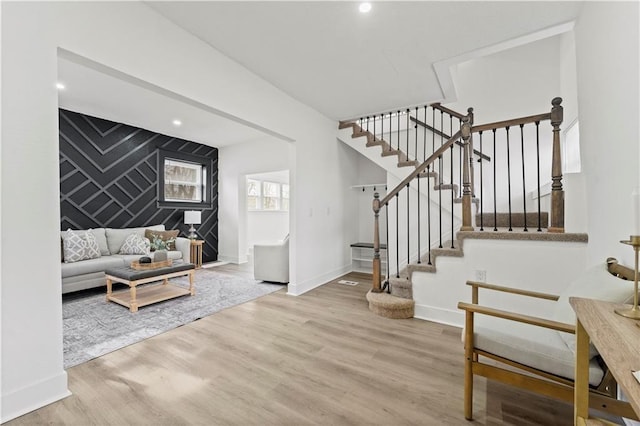 living room featuring an accent wall, recessed lighting, wood finished floors, and baseboards