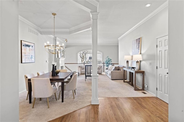 dining room featuring a chandelier, wood finished floors, visible vents, ornamental molding, and decorative columns