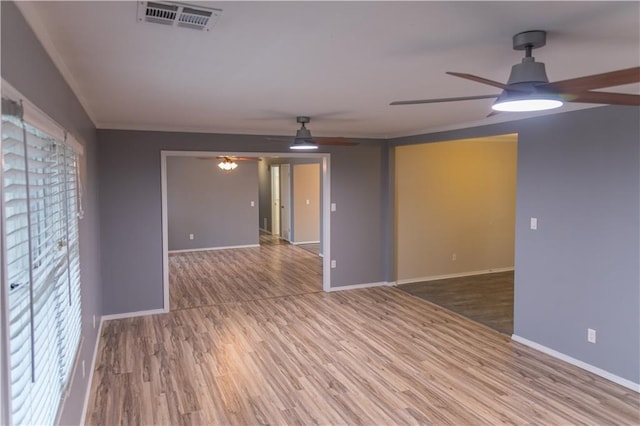 empty room with crown molding, wood-type flooring, and ceiling fan