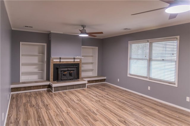 unfurnished living room featuring crown molding, ceiling fan, built in shelves, and hardwood / wood-style floors