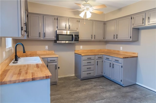 kitchen featuring gray cabinets, ceiling fan, sink, and butcher block countertops