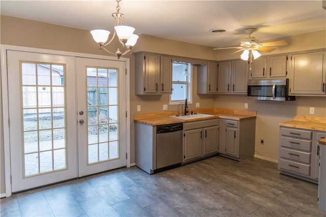 kitchen featuring french doors, wood counters, sink, decorative light fixtures, and appliances with stainless steel finishes