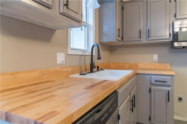 kitchen featuring butcher block counters, sink, stainless steel appliances, and gray cabinetry