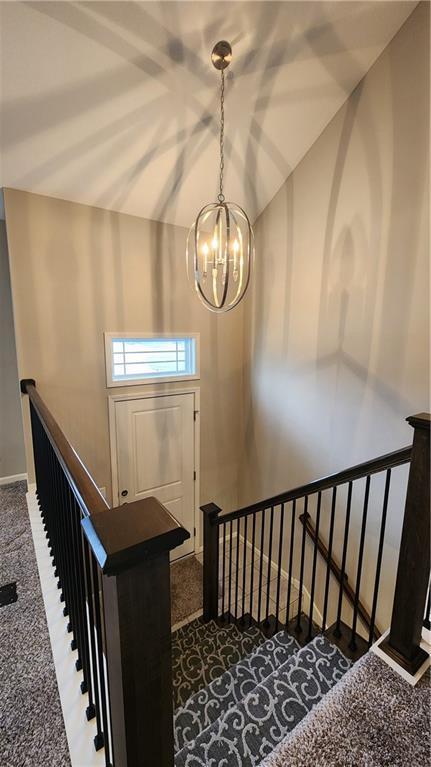 stairway featuring carpet flooring and a chandelier