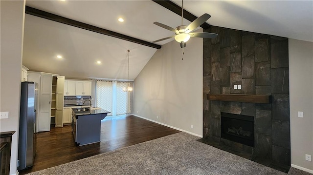 kitchen with stainless steel fridge, a breakfast bar, beam ceiling, an island with sink, and white cabinets