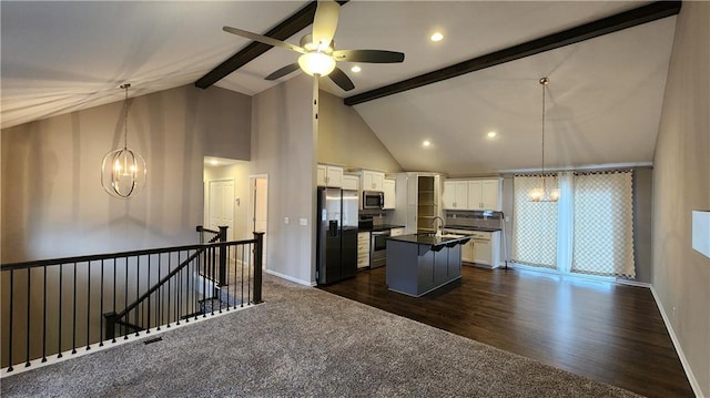 kitchen featuring decorative light fixtures, an island with sink, beamed ceiling, stainless steel appliances, and white cabinets