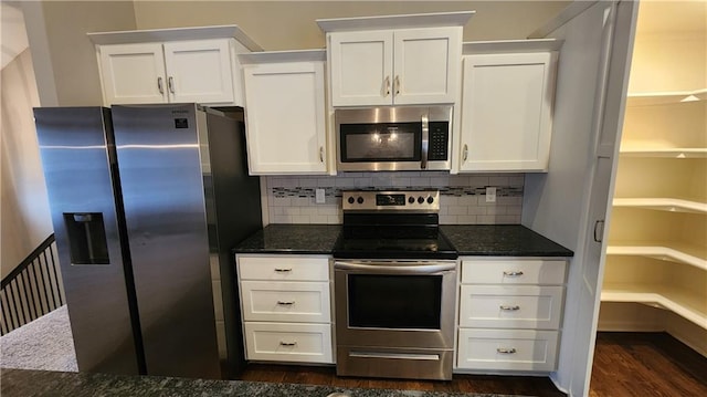 kitchen featuring appliances with stainless steel finishes, white cabinets, backsplash, and dark stone counters