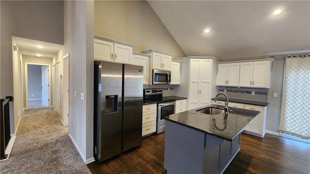 kitchen featuring sink, appliances with stainless steel finishes, an island with sink, dark stone counters, and white cabinets