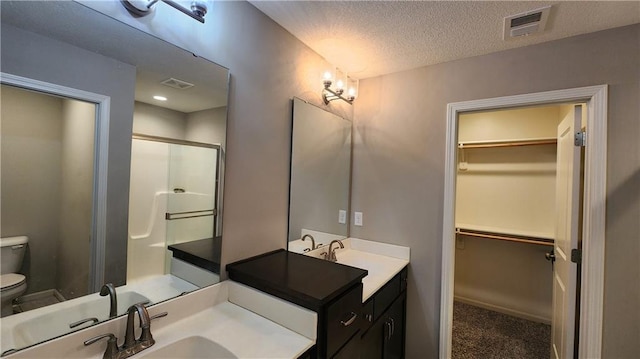 bathroom with vanity, an enclosed shower, a textured ceiling, and toilet