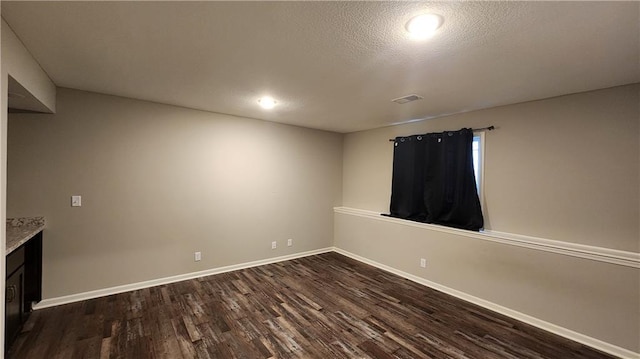 unfurnished room featuring a textured ceiling and dark hardwood / wood-style flooring