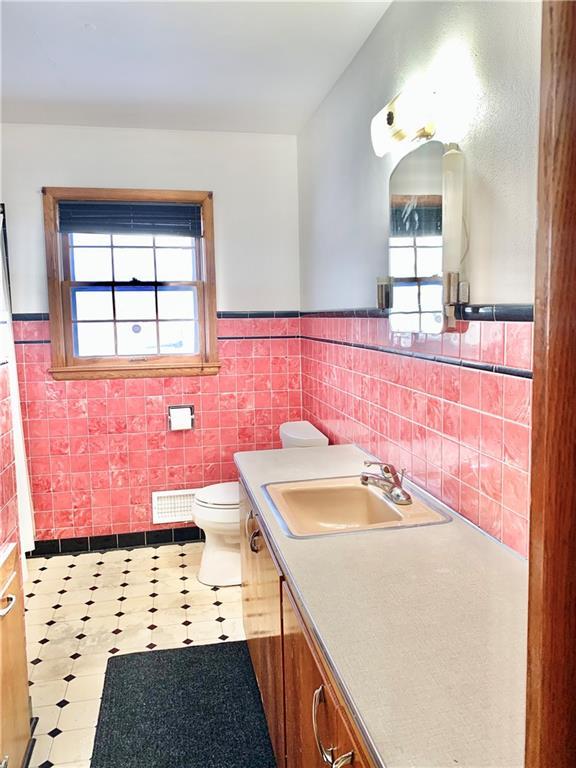 bathroom featuring vanity, toilet, and tile walls