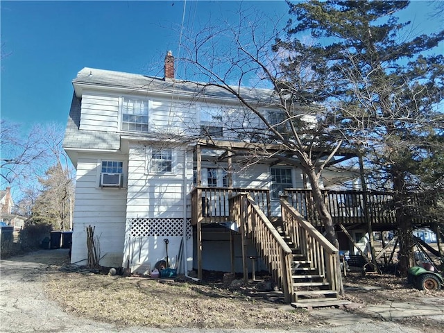 view of front of property featuring cooling unit, a chimney, stairway, and a wooden deck