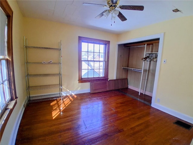 unfurnished bedroom with a closet, wood finished floors, visible vents, and baseboards