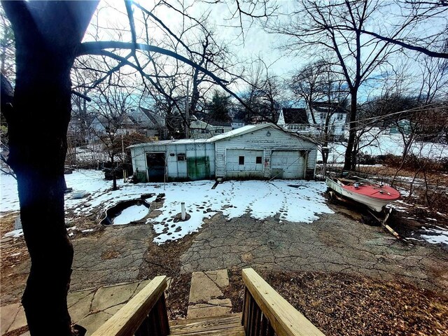 view of snowy exterior featuring a detached garage and an outbuilding