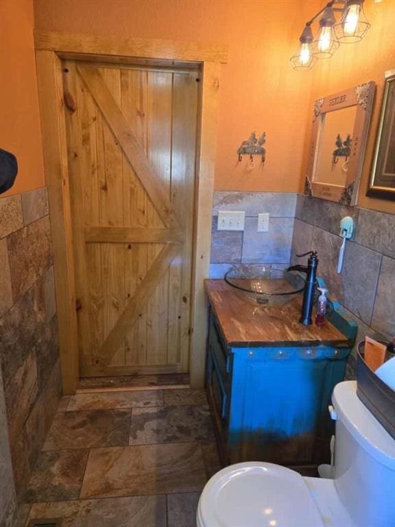 bathroom featuring tile walls, vanity, and toilet