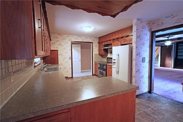 kitchen with sink, ceiling fan, white fridge with ice dispenser, decorative backsplash, and range with two ovens