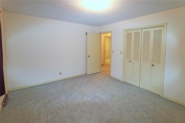 unfurnished bedroom featuring light colored carpet and a closet