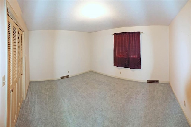 unfurnished bedroom with a closet, vaulted ceiling, and light carpet