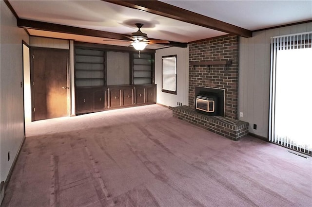 unfurnished living room featuring carpet, visible vents, ceiling fan, wood walls, and beamed ceiling