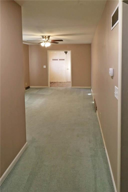 hallway featuring baseboards and light colored carpet