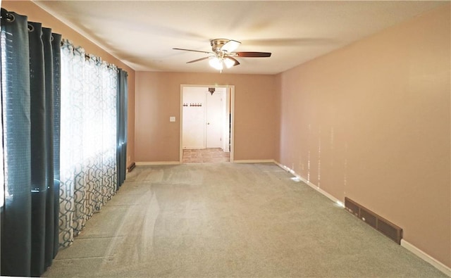 empty room featuring visible vents, baseboards, carpet floors, and ceiling fan