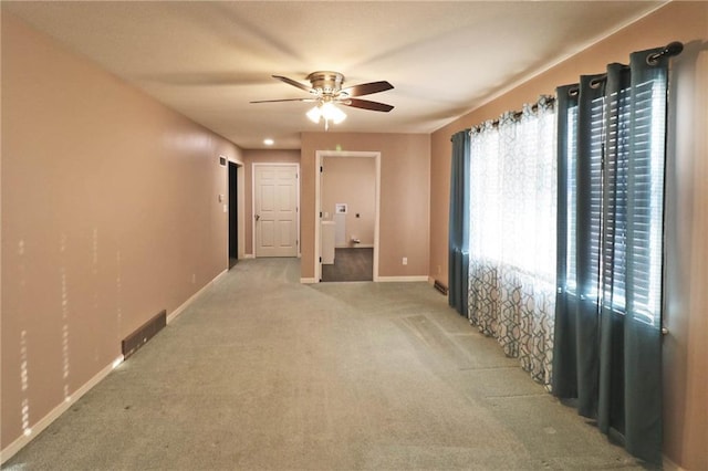 empty room featuring light carpet, visible vents, ceiling fan, and baseboards