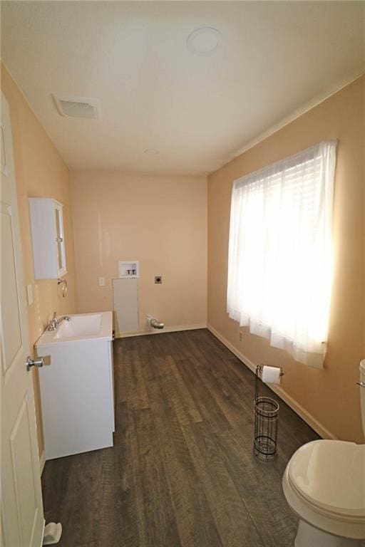 half bathroom with vanity, toilet, wood finished floors, and baseboards