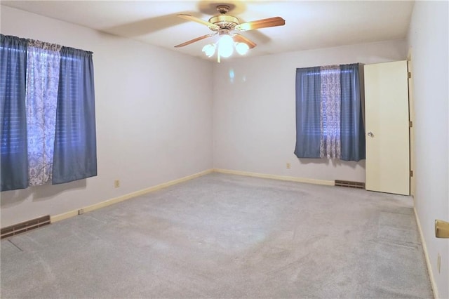 carpeted spare room featuring visible vents, baseboards, and ceiling fan