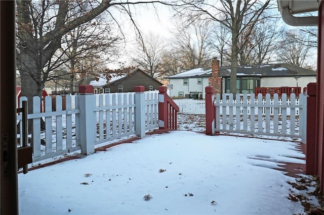 yard covered in snow with a residential view and fence