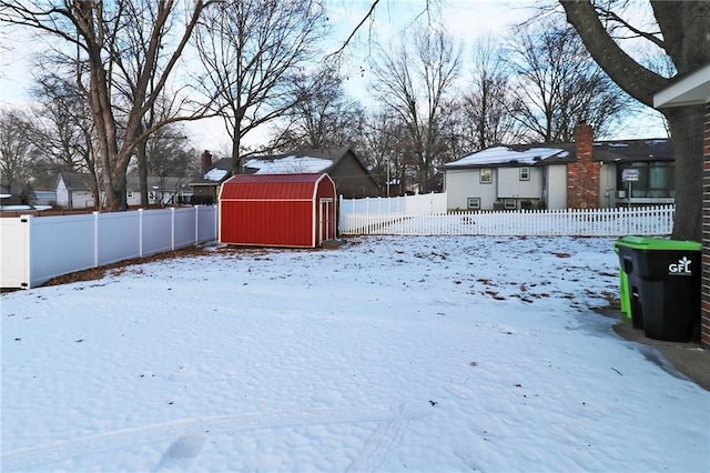 yard covered in snow featuring an outbuilding, a storage shed, and a fenced backyard