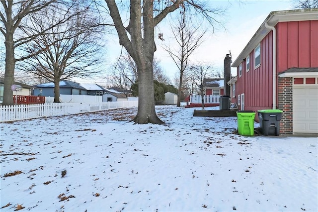 yard layered in snow featuring a residential view, central AC unit, a garage, and fence