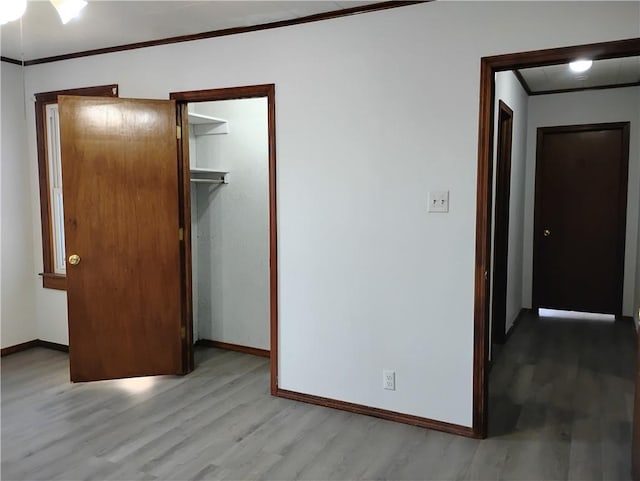 unfurnished bedroom featuring crown molding, light wood-type flooring, and a closet