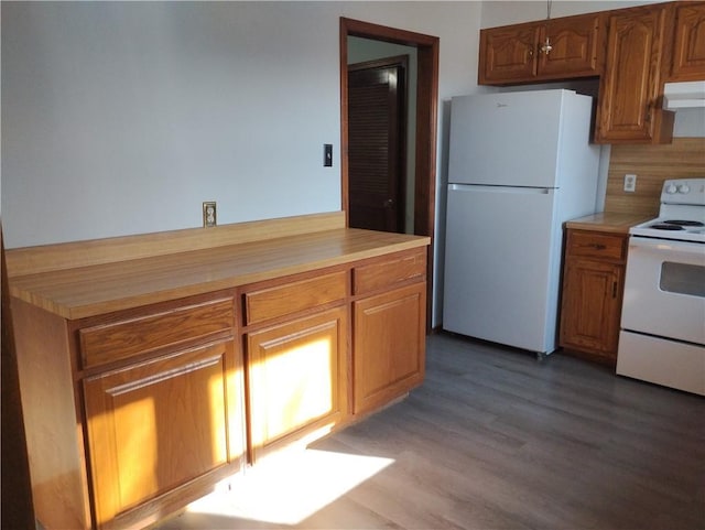 kitchen featuring exhaust hood, backsplash, white appliances, and wood-type flooring