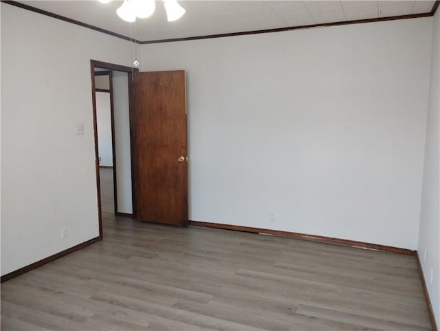 empty room with crown molding and light hardwood / wood-style floors