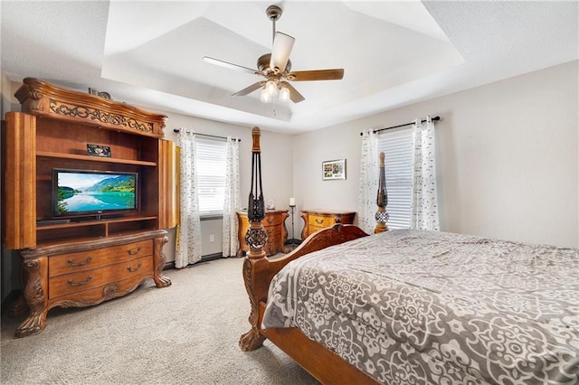 bedroom with ceiling fan, a tray ceiling, and carpet flooring