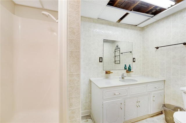 bathroom with vanity, tile walls, and toilet