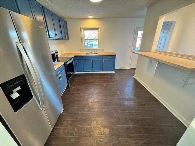 kitchen featuring dark wood-type flooring, blue cabinetry, appliances with stainless steel finishes, and wooden counters