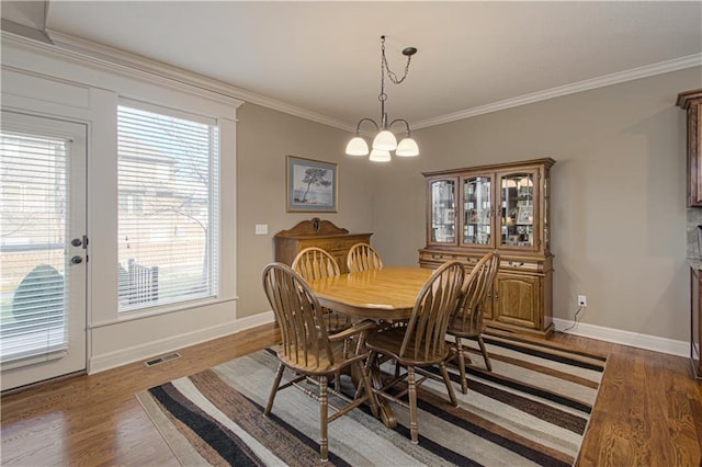 dining area with an inviting chandelier, ornamental molding, and light hardwood / wood-style floors