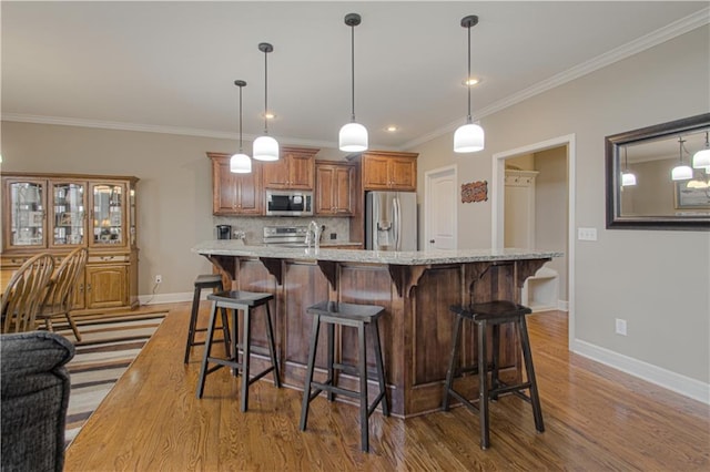 kitchen with appliances with stainless steel finishes, a large island, light stone counters, and decorative light fixtures