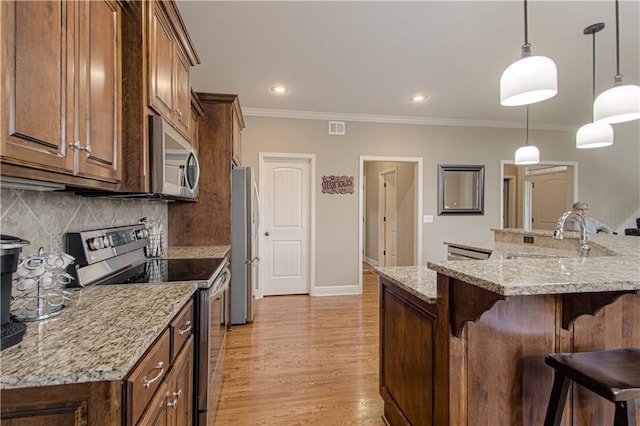 kitchen with pendant lighting, sink, a breakfast bar, appliances with stainless steel finishes, and light stone countertops