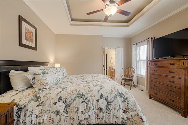 carpeted bedroom with crown molding, connected bathroom, ceiling fan, and a tray ceiling