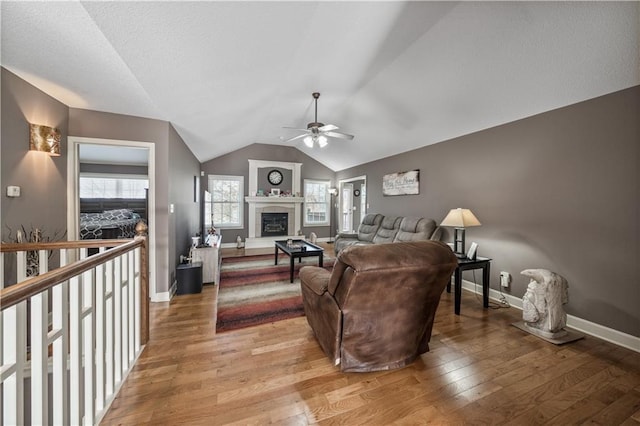 living room featuring ceiling fan, lofted ceiling, hardwood / wood-style floors, and a fireplace