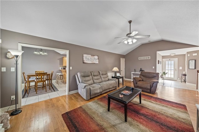 living room featuring ceiling fan with notable chandelier, lofted ceiling, and light hardwood / wood-style floors