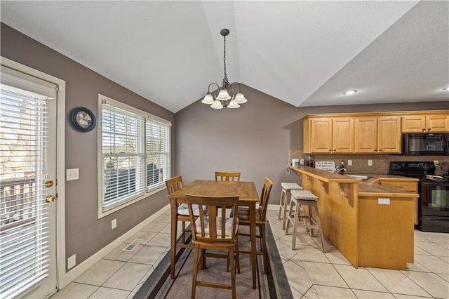 kitchen with lofted ceiling, a kitchen bar, black appliances, light tile patterned floors, and backsplash