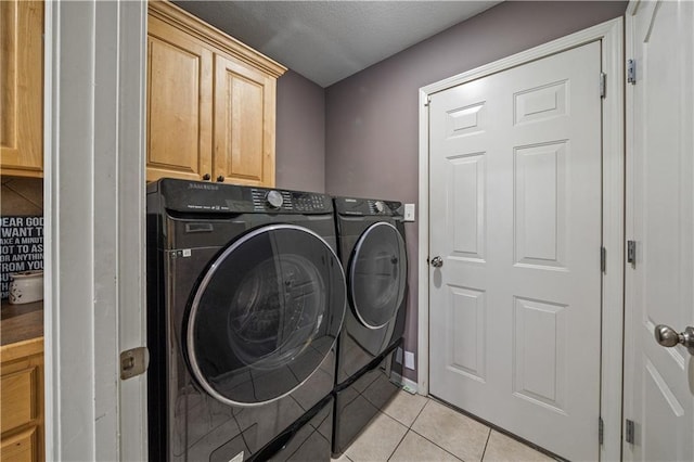 laundry area with cabinets, light tile patterned floors, and washing machine and clothes dryer