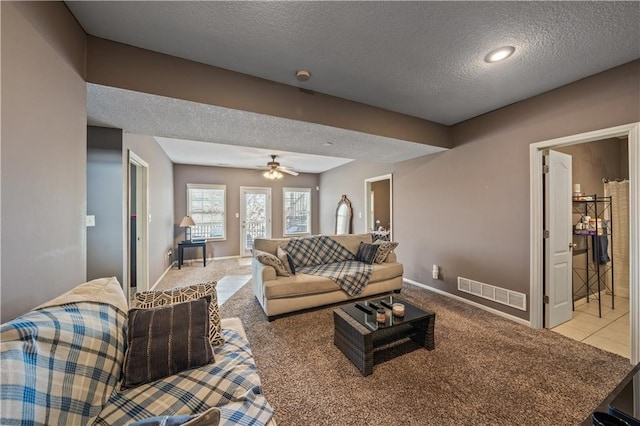 living room with ceiling fan, light colored carpet, and a textured ceiling