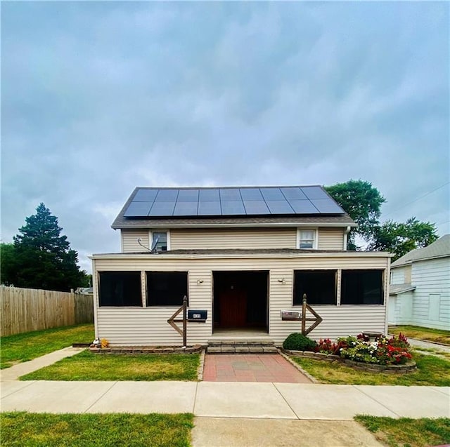 view of front of property featuring a front lawn and solar panels